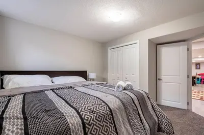 a bedroom with a bed with two towels on it at Luxurious Comfortable Suite in Airdrie