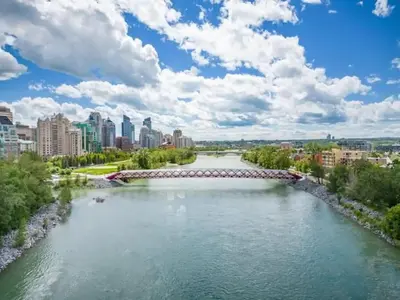 a bridge over a river with a city in the background at Luxurious Comfortable Suite in Airdrie