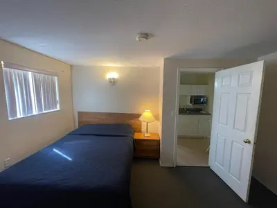 a bedroom with a bed and a window and a door at Fraser Bridge Inn in Quesnel