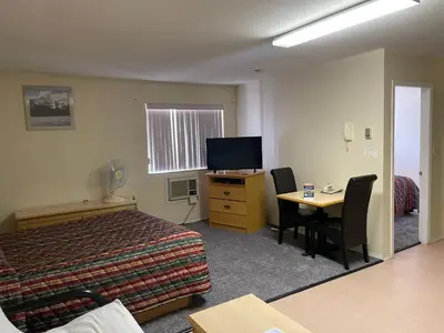 a hotel room with a bed and a desk and a television at Fraser Bridge Inn in Quesnel