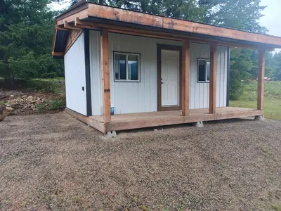 a tiny house with a porch on a gravel yard at Wells Gray Stay And Play in Clearwater