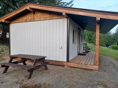 a wooden cabin with a picnic table and a bench at Wells Gray Stay And Play in Clearwater