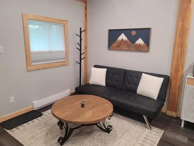 a living room with a black couch and a table at Wells Gray Stay And Play in Clearwater