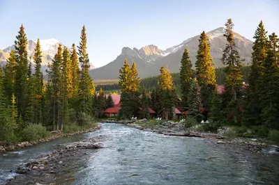a river flows through a forest with mountains at Post Hotel & Spa in Lake Louise