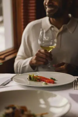 a man sitting at a table with a plate of food and a wine glass at Post Hotel & Spa in Lake Louise