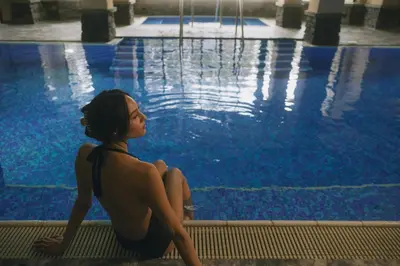 a woman sitting next to a swimming pool at Post Hotel & Spa in Lake Louise