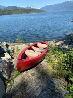 a red canoe sitting on the shore of a lake at Earls Cove Orca View in Egmont