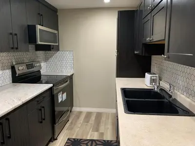 a kitchen with black cabinets and a sink at Divine Homes in Calgary