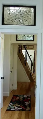 a hallway with a staircase with a stained glass window at Thistle Dew Cottage in Ganges