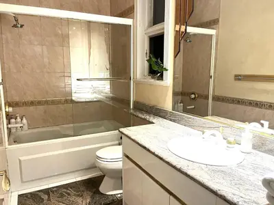 a bathroom with a tub and a toilet and a sink at Van Nest near YVR UBC Downtown in Vancouver