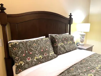 a bed with a wooden headboard with two pillows at Van Nest near YVR UBC Downtown in Vancouver