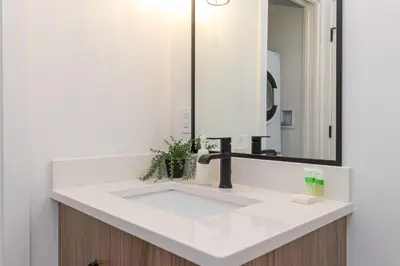 a bathroom with a white sink and a mirror at Be Close To Chinatown When You Are In The Ironwork Building in Victoria