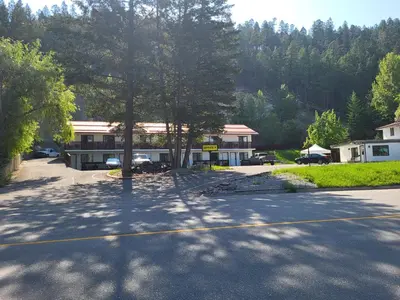 a parking lot in front of a house with a tree at Alpen Motel in Radium Hot Springs