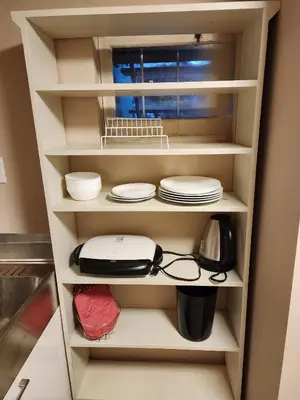 a kitchen shelf with plates and dishes on it at Economical Homestay hostel in Burnaby