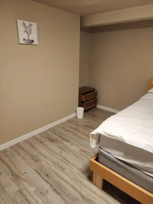 a bedroom with a bed and a wooden floor at Economical Homestay hostel in Burnaby