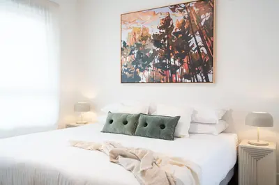a bedroom with a white bed with a painting on the wall at Cabot Views by Revelstoke Vacations in Revelstoke
