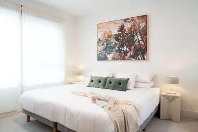 a bedroom with a white bed with a painting on the wall at Cabot Views by Revelstoke Vacations in Revelstoke