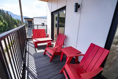 three red chairs and a table on a balcony at Stoke House by Revelstoke Vacations in Revelstoke