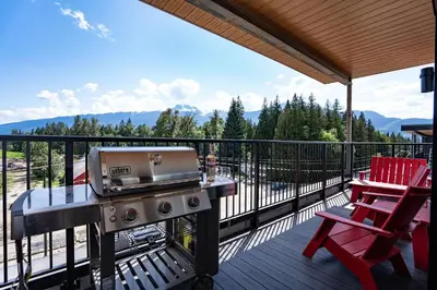 a grill on a deck with a table and a chair at Stoke House by Revelstoke Vacations in Revelstoke