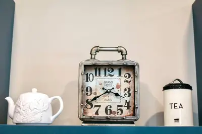 an old clock sitting on a shelf next to a tea kettle at RainCoast Retreat at Shawnigan Lake! in Shawnigan Lake