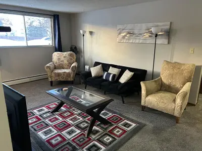 a living room with a couch and chairs and a table at One Bedroom Main floor Apartment in Camrose