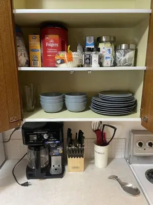 a kitchen cabinet filled with plates and utensils at Stunning 1 Bedroom Apartment in Camrose
