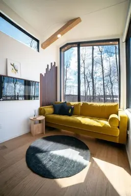 a living room with a yellow couch and a large window at Refuge Bay's Aqua Tiny Home - Luxury Off Grid Escape in Cherhill