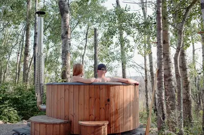 two people sitting in a hot tub in the woods at Refuge Bay's Aqua Tiny Home - Luxury Off Grid Escape in Cherhill