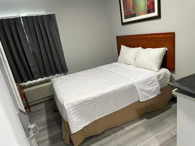 a bedroom with a large bed with white sheets at RAMSHORN MOTEL in Lumby