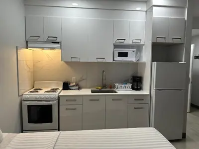 a kitchen with white cabinets and a stove and a refrigerator at RAMSHORN MOTEL in Lumby