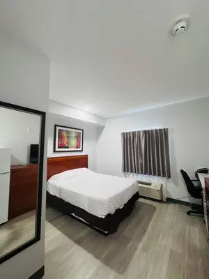 a bedroom with a bed and a desk and a mirror at RAMSHORN MOTEL in Lumby