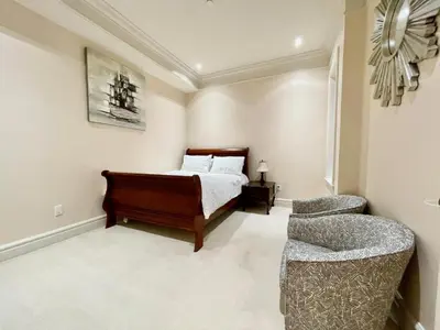 a bedroom with a bed and a chair at Vancouver Airport guesthouse in Vancouver