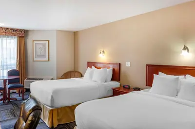 a hotel room with two beds and a table at Quality Inn & Suites Edmonton International Airport in Leduc