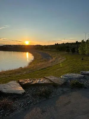 a sunset over a body of water with rocks at 2 Bedroom 2 Washrooms Brand New Beautiful & Cozy Suite in Calgary