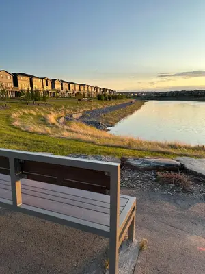 a bench sitting next to a body of water at 2 Bedroom 2 Washrooms Brand New Beautiful & Cozy Suite in Calgary