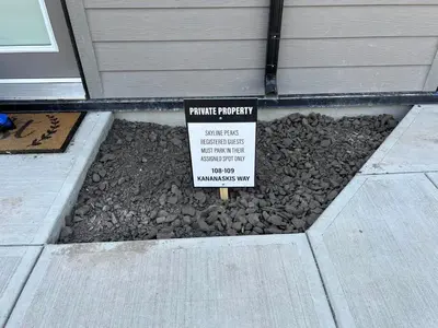 a sign in a bed of rocks next to a house at Mountain View Studio in Town in Canmore
