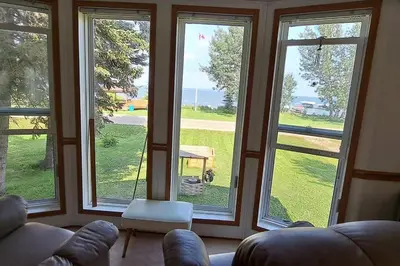 a living room with large windows with a view of the ocean at 4 Seasons Lakeview Cottage w/ Private Boating Dock in Westerose