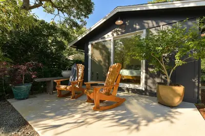 a patio with two chairs and a table and a house at The Bayside Cottage by EMR Vacation Rentals in North Saanich