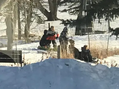 a group of people and a dog in the snow at Rolling Hills Country Resort Bed and Breakfast in Three Hills