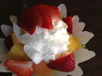 a fruit salad with whipped cream and strawberries on a plate at Rolling Hills Country Resort Bed and Breakfast in Three Hills