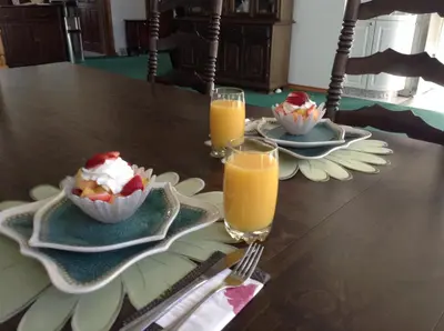 a table with two plates of food and two glasses of orange juice at Rolling Hills Country Resort Bed and Breakfast in Three Hills