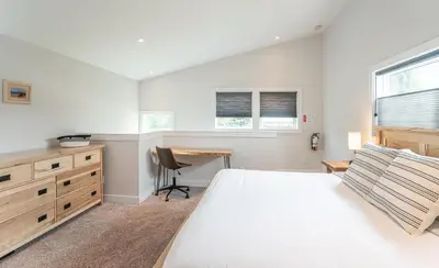 a bedroom with a bed and a desk and windows at Mountain Dreams - Revelstoke Home Near RMR in Revelstoke