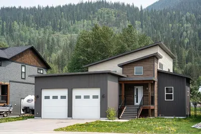 a house with two garage doors in front of a house at Mountain Dreams - Revelstoke Home Near RMR in Revelstoke