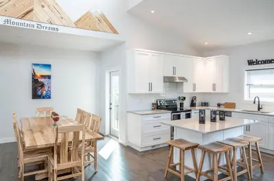 a kitchen with white cabinets and a table and chairs at Mountain Dreams - Revelstoke Home Near RMR in Revelstoke