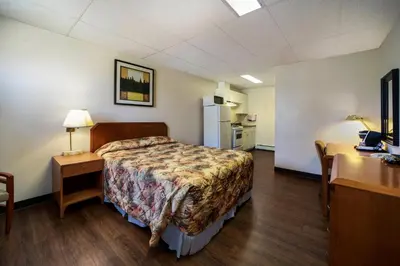 a room with a bed and a desk and a refrigerator at Canadas Best Value Inn Fort St John in Fort Saint John