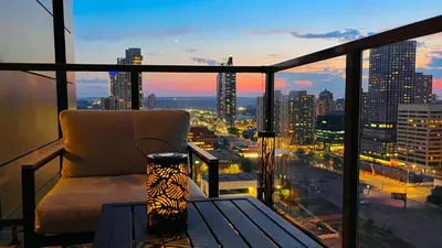 a room with a chair and a view of a city at LUXURY Downtown Sunset Getaway - Your Home Away From Home - Fully Stocked Kitchen, Gym, Balcony, FREE PARKING in Calgary