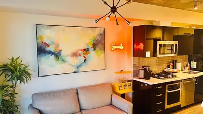 a living room with a couch and a kitchen at LUXURY Downtown Sunset Getaway - Your Home Away From Home - Fully Stocked Kitchen, Gym, Balcony, FREE PARKING in Calgary