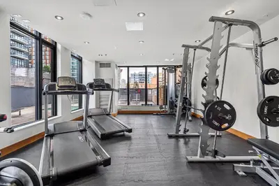 a gym with two treadmills and two tread machines at LUXURY Downtown Sunset Getaway - Your Home Away From Home - Fully Stocked Kitchen, Gym, Balcony, FREE PARKING in Calgary