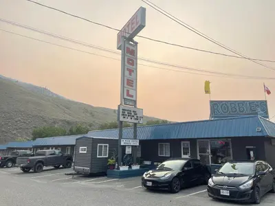 a motel with two cars parked in a parking lot at Robbie's Motel in Cache Creek