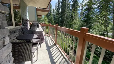 a balcony of a house with a table and chairs at Spacious King Bed with Pool & Hot Tubs in Canmore